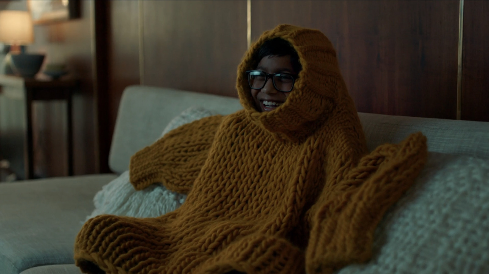 a person in a sweater sitting on a bed