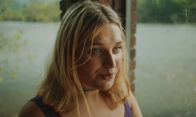 a woman looking out a window by a river