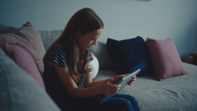 a girl sitting on a couch using a tablet