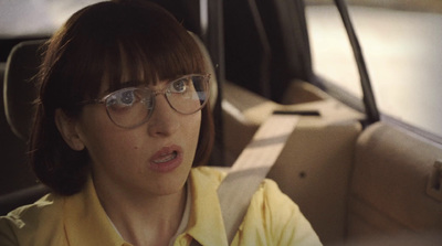 a woman wearing glasses sitting in a car