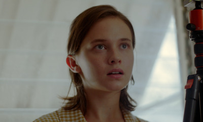 a young girl with a camera in front of a window