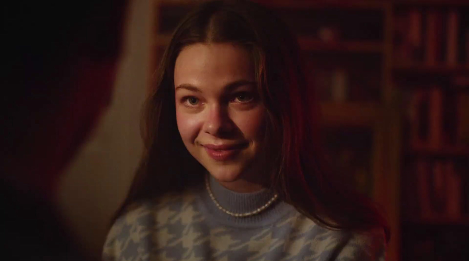  a woman with a pearl necklace smiling at the camera