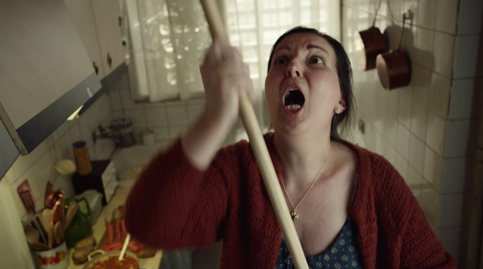 a woman holding a wooden stick in a kitchen