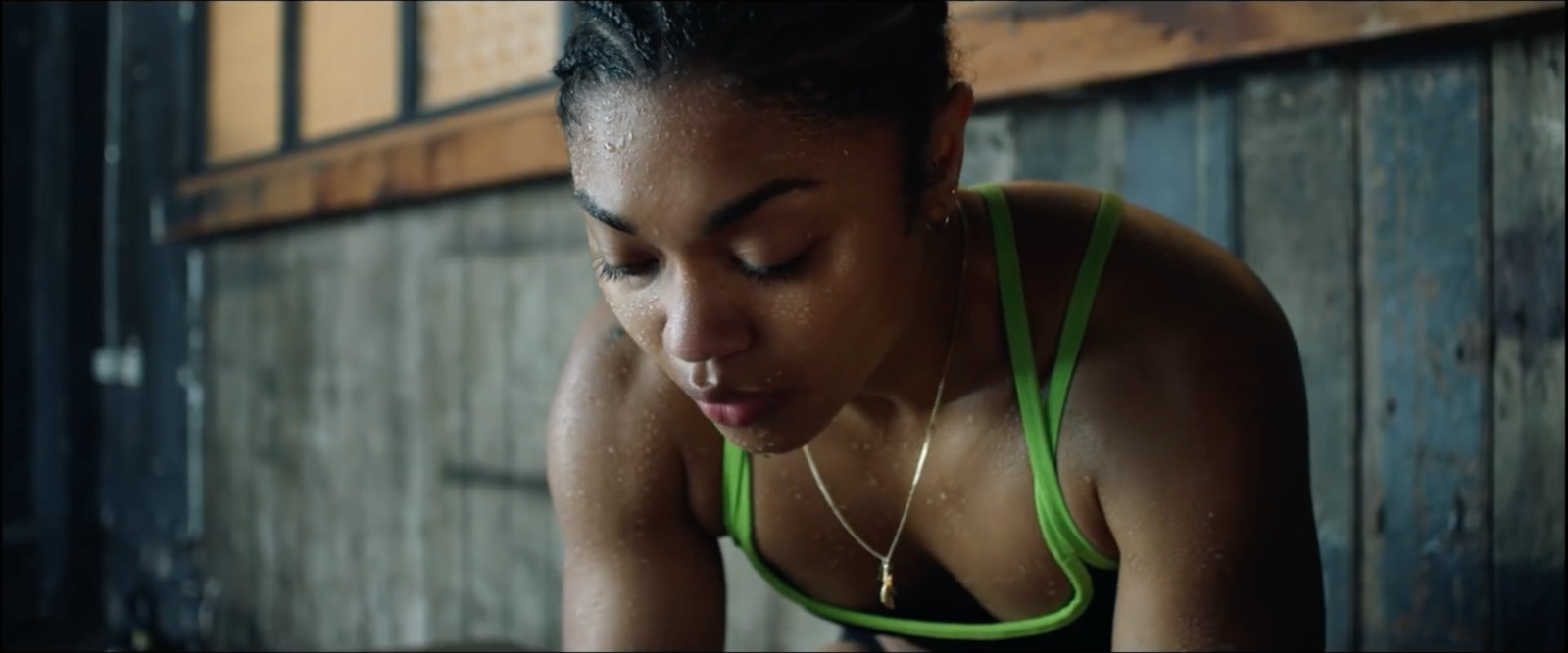 a woman in a green tank top looking down at her phone