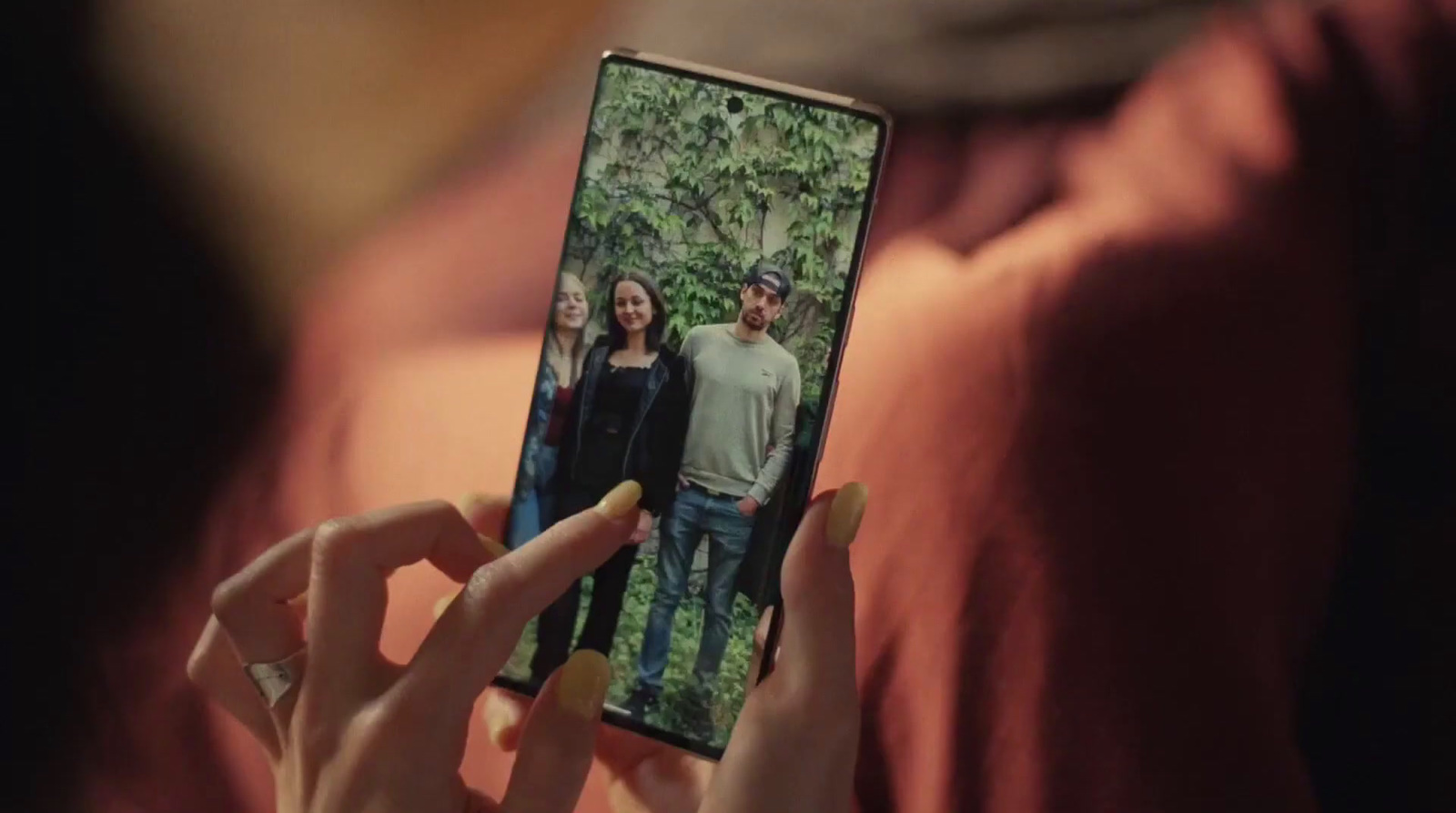 a woman holding up a cell phone with a picture of a family on it