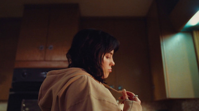 a woman in a hoodie standing in a kitchen