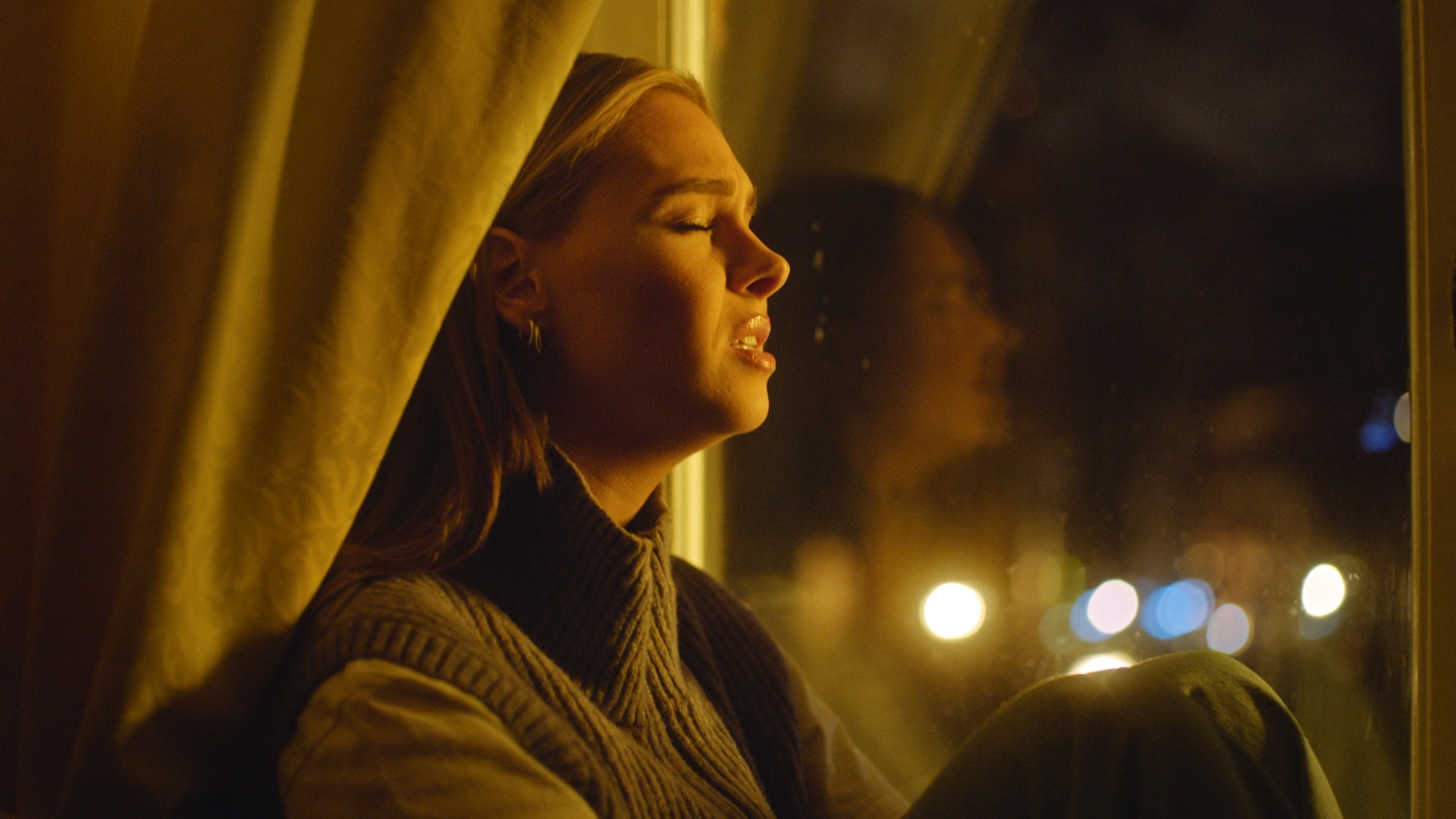  a woman sitting in front of a window with her eyes closed