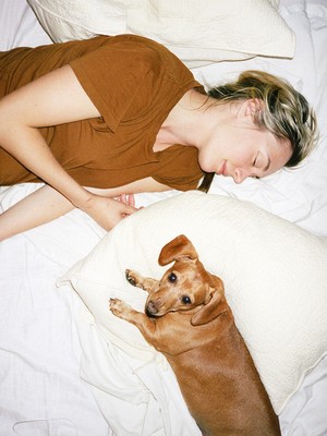 a woman laying in bed next to a brown dog