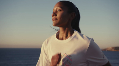 a woman in a white shirt running by the ocean