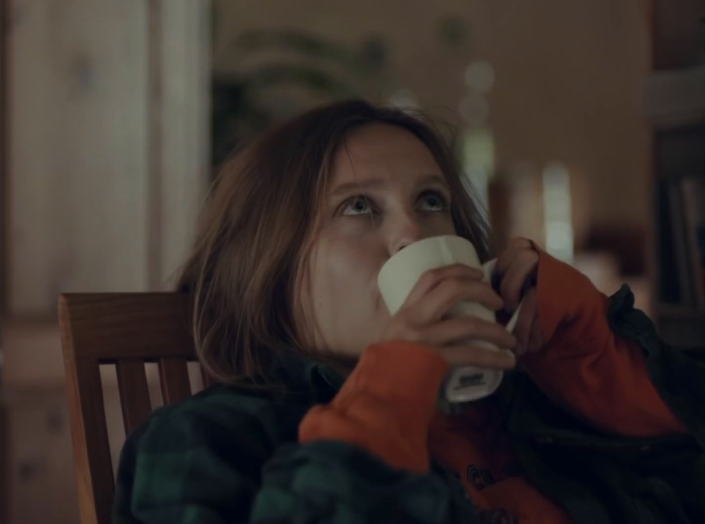 a woman sitting in a chair drinking a cup of coffee