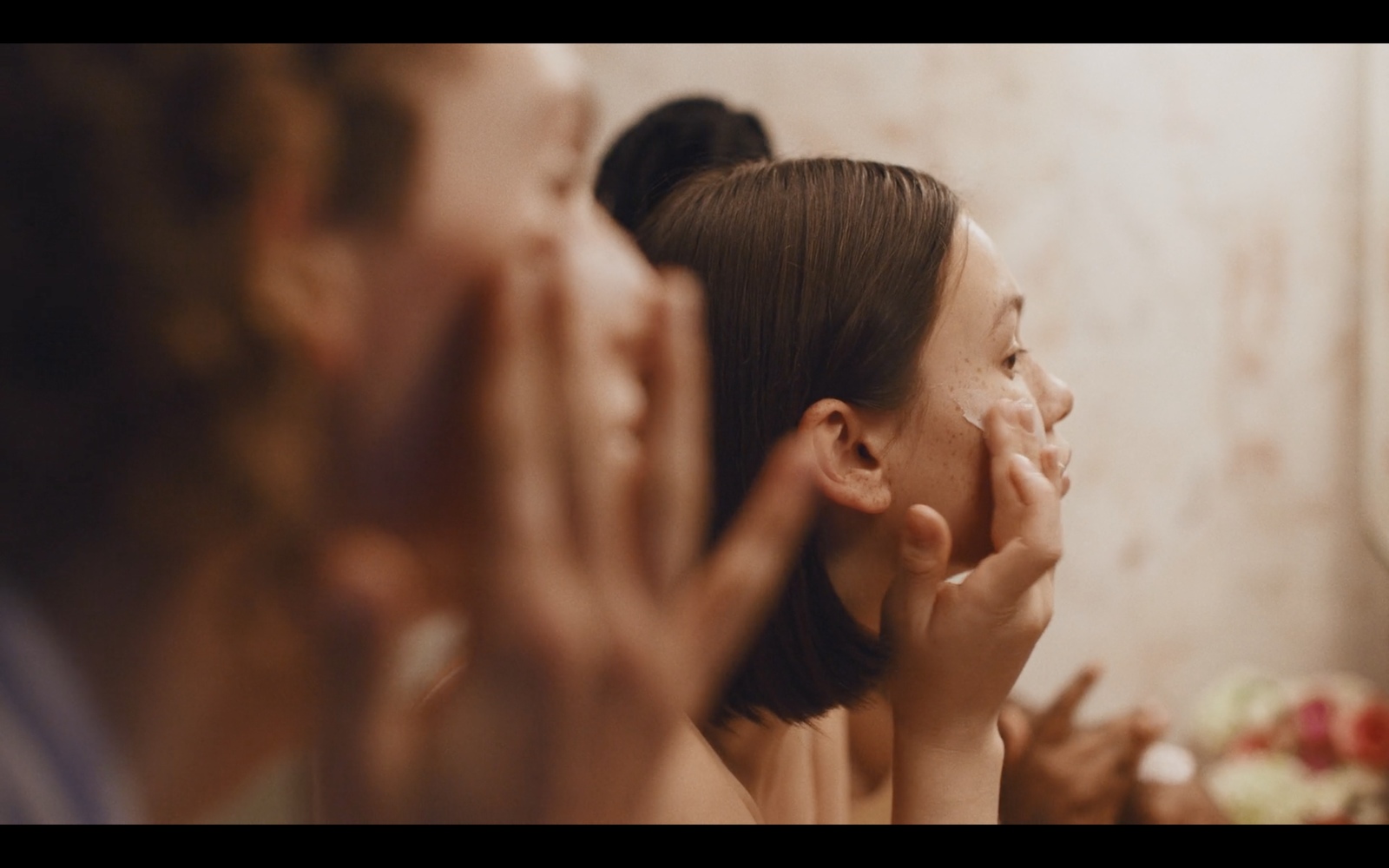 a group of women are touching their faces in front of a mirror