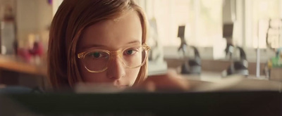 a girl wearing glasses is looking at a book