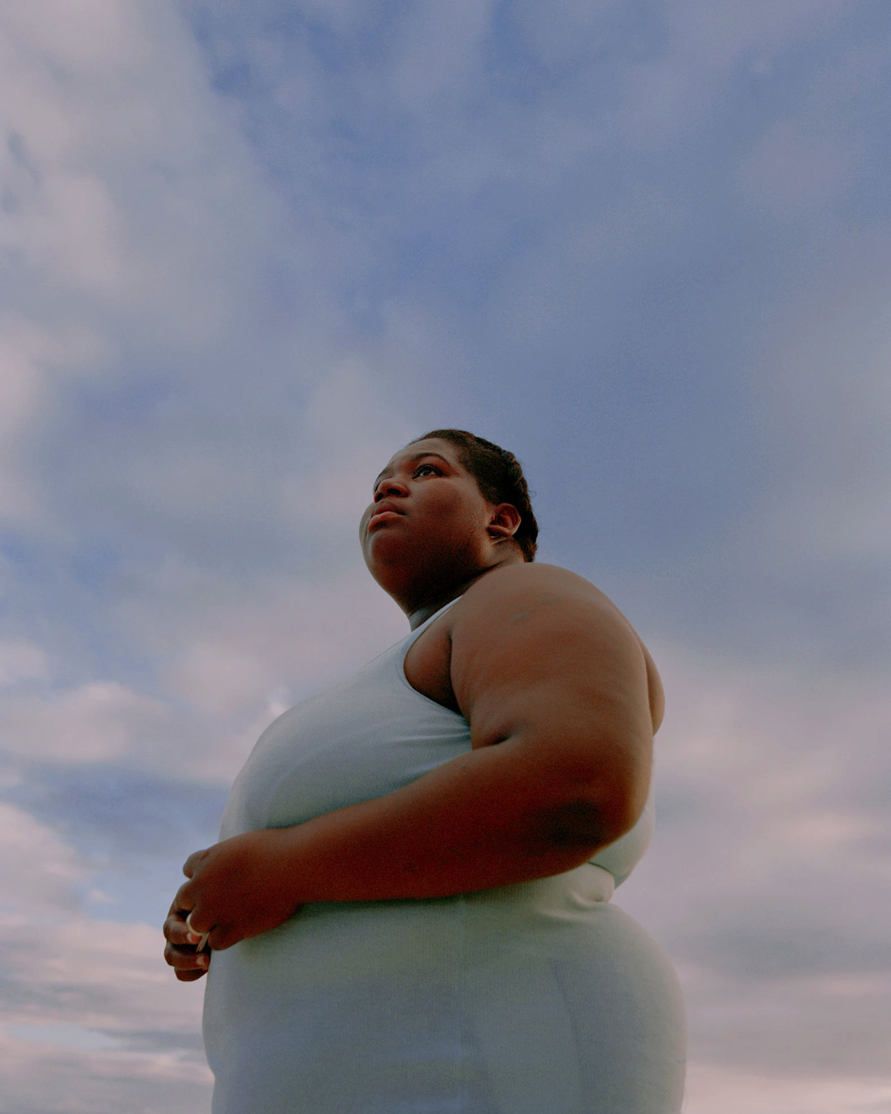 a woman standing in a field with her arms crossed