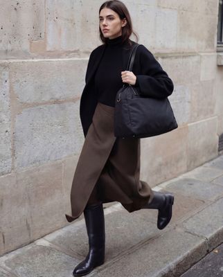 a woman is walking down the street carrying a black bag