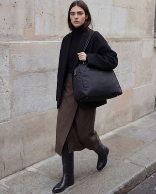 a woman walking down the street carrying a black bag