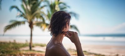 a man standing on a beach next to a palm tree