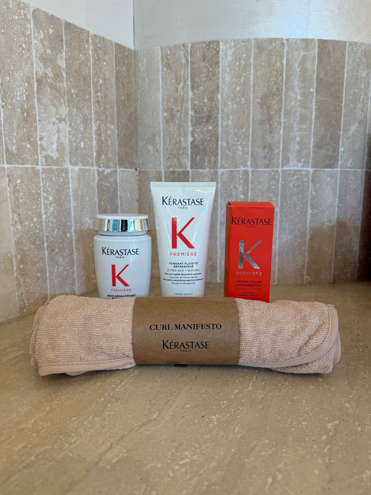 a bathroom counter with a towel, lotion, and a tube of keras