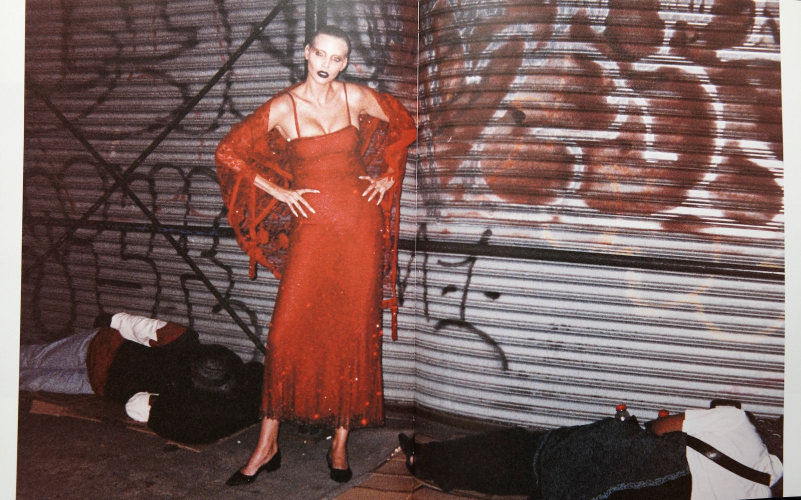 a woman in a red dress standing in front of a graffiti covered wall