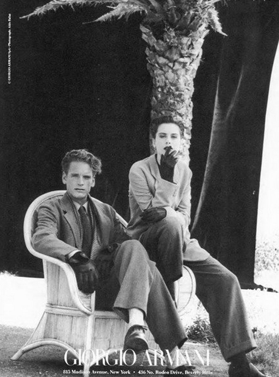 a black and white photo of two men sitting on a bench