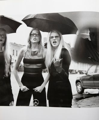 a black and white photo of three women with umbrellas