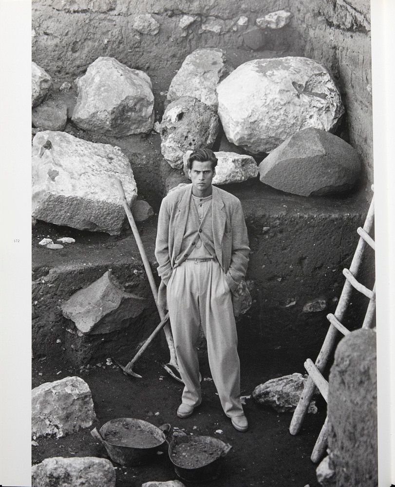 a black and white photo of a man standing in front of rocks