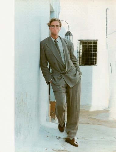 a man in a suit leaning against a wall