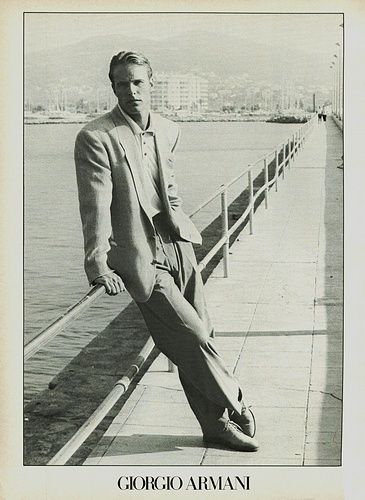 a black and white photo of a man leaning on a pier