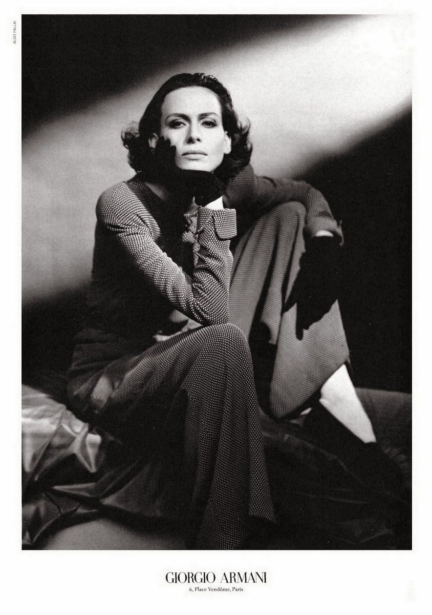 a black and white photo of a woman sitting on a bed