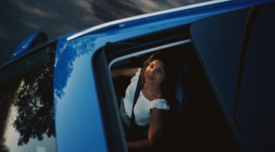 a woman sitting in the back of a blue car