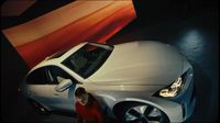 a woman standing next to a silver car on display