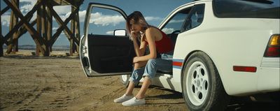 a woman sitting on the back of a white car