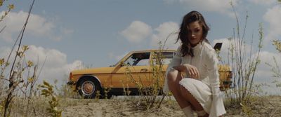 a woman sitting on the ground next to a car