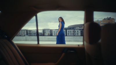 a woman in a blue dress standing in front of a window