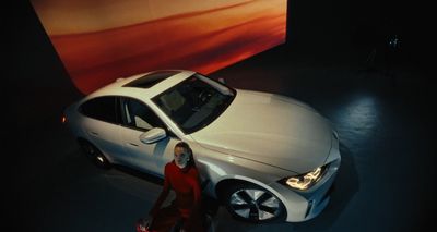 a woman standing next to a white car on display