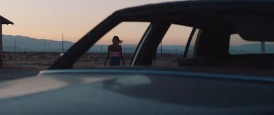 a woman standing next to a car in the desert