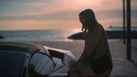 a woman standing next to a parked car