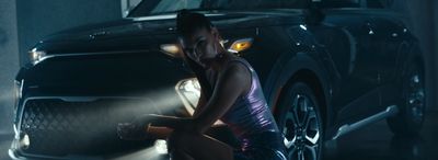 a woman sitting on the ground next to a car