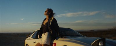 a woman leaning on the hood of a car