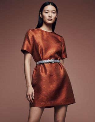 a woman in an orange dress posing for a picture