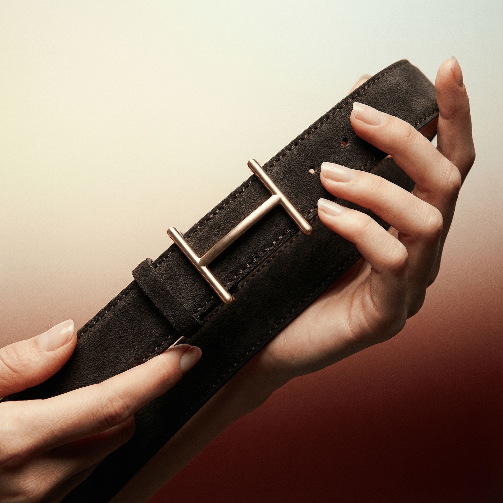 a woman's hands holding a black leather belt