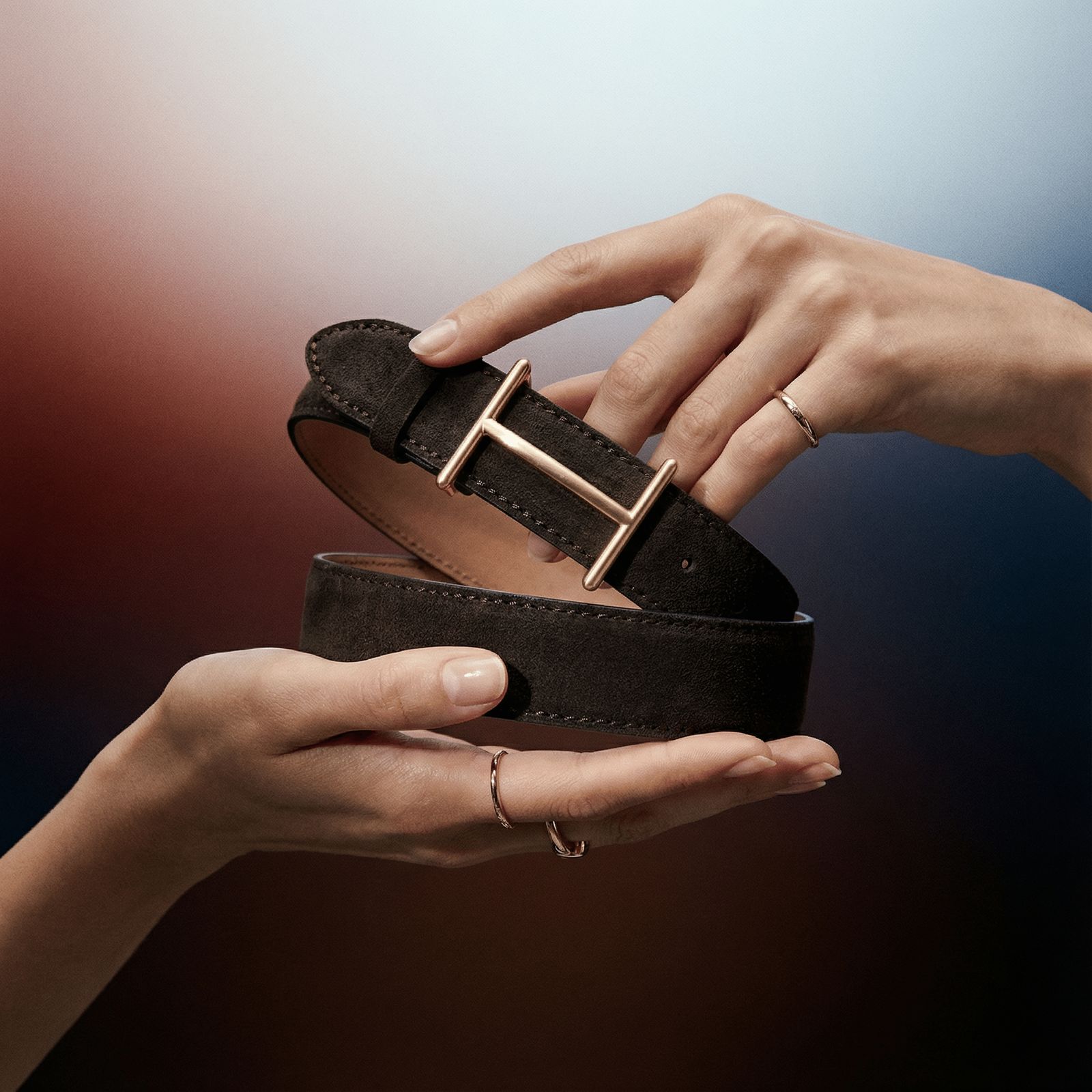 a pair of hands holding a pair of black leather belts