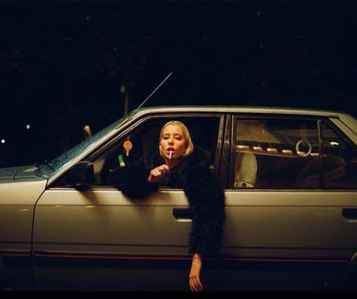 a woman sitting in a car smoking a cigarette