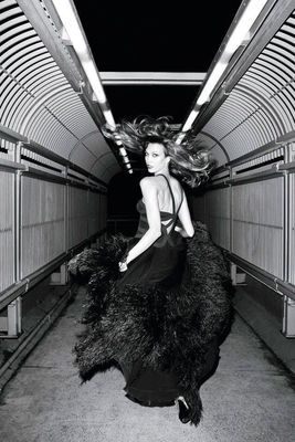 a woman in a black dress is standing in a tunnel
