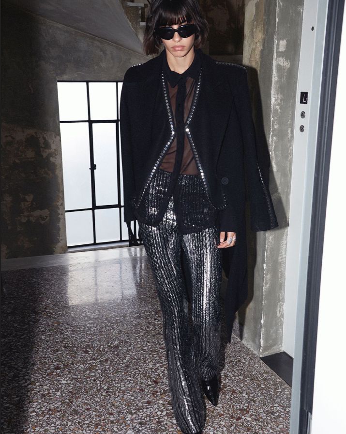 a woman in a black jacket and silver pants