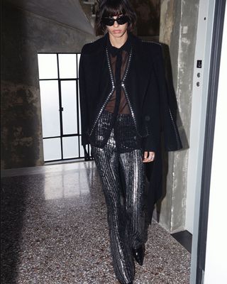 a woman in a black jacket and silver pants