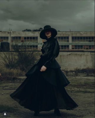 a woman in a long black dress and hat