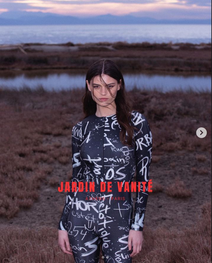 a woman standing in a field next to a body of water