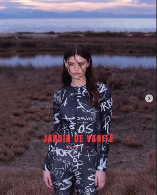 a woman standing in a field next to a body of water