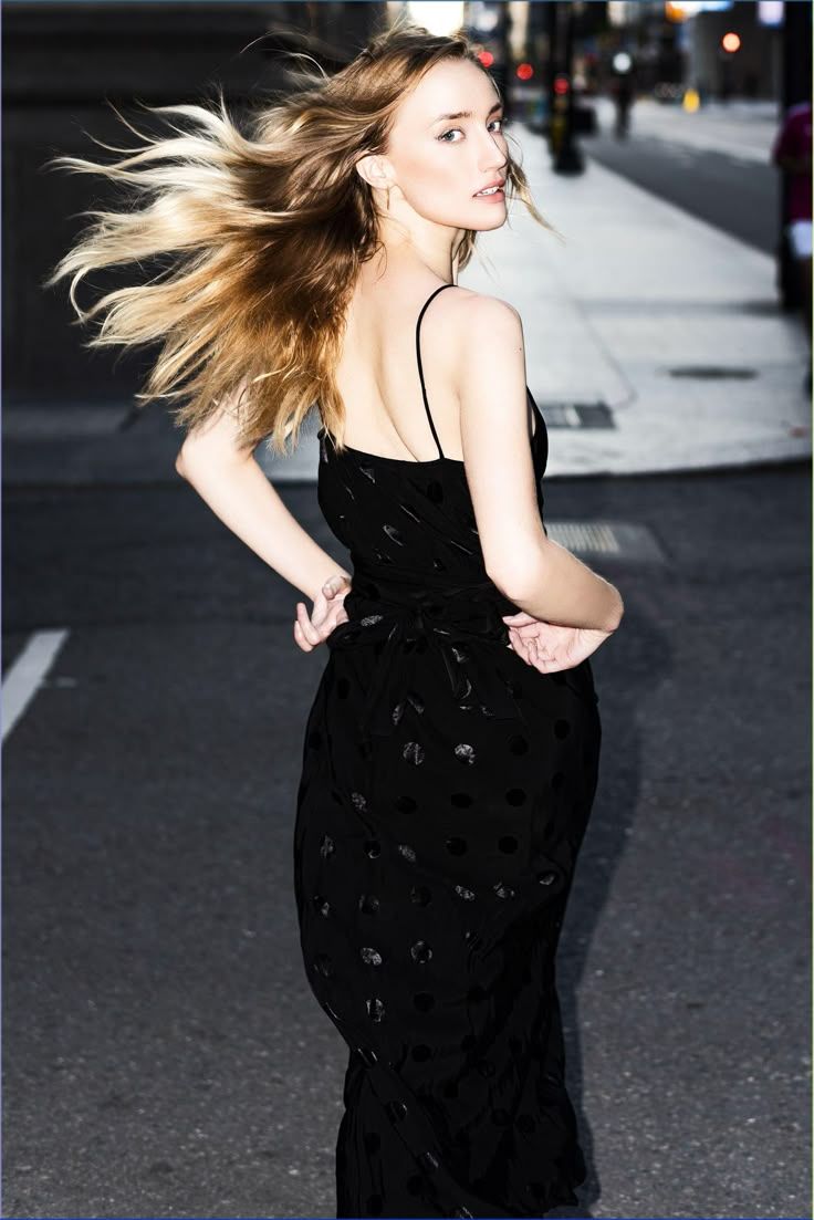 a woman with long hair walking down a street