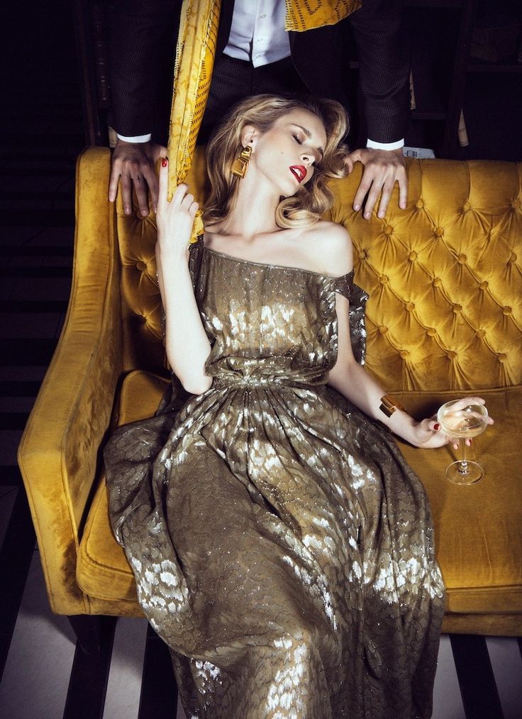 a woman in a gold dress sitting on a couch